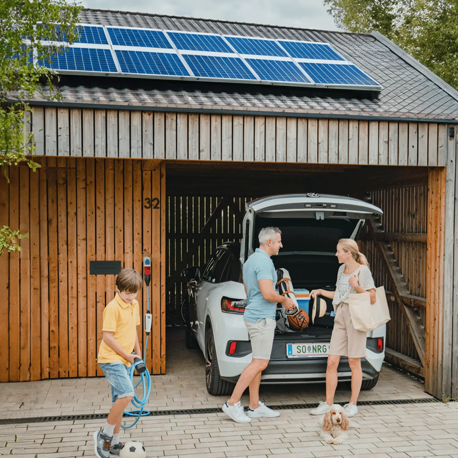 Intelligente Wallbox-NRGkick lädt Elektroauto einer Familie mit PV-Anlage auf dem Dach.