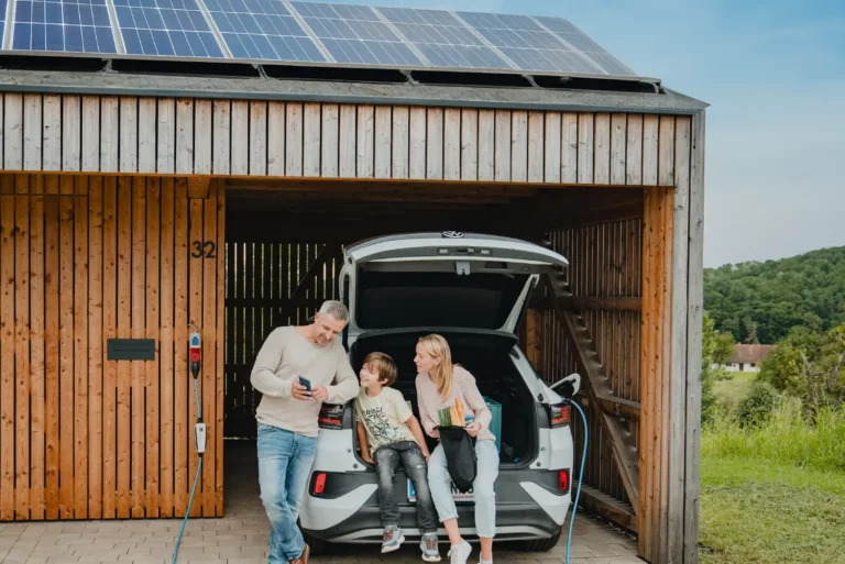 Familie betrachtet die NRGkick-App an während das E-Auto mit PV-Strom lädt.